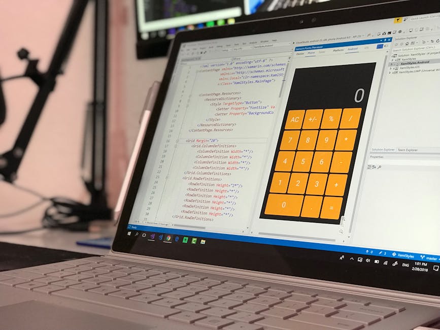 Close-up of a person's hands operating a laptop on a dark table, displaying the screen with visible lines of code and text, indicating a coding or programming session. The environment appears to be in